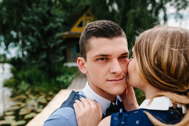 Young couple kissing on a wooden bridge above the lake