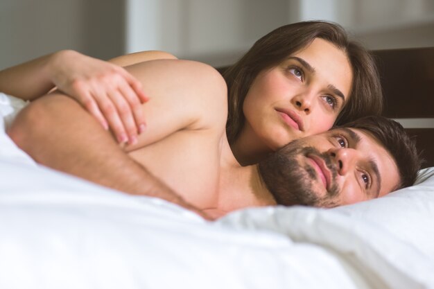 The young couple lay in the white linens on the bed