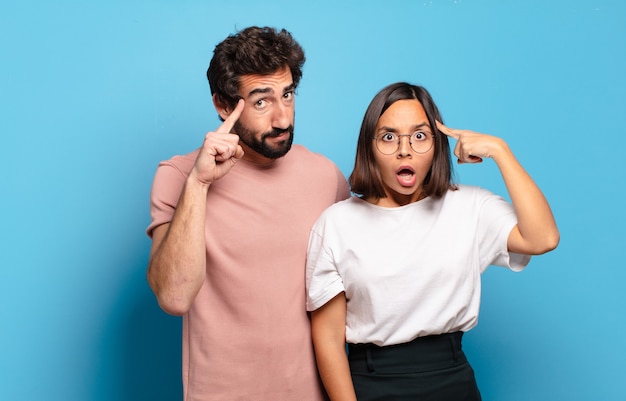 Young couple looking surprised, open-mouthed, shocked, realizing a new thought, idea or concept