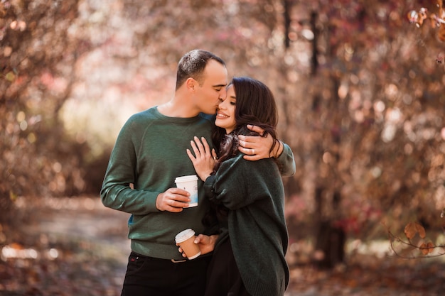 young couple in love drinking coffee on a walk in the autumn forest