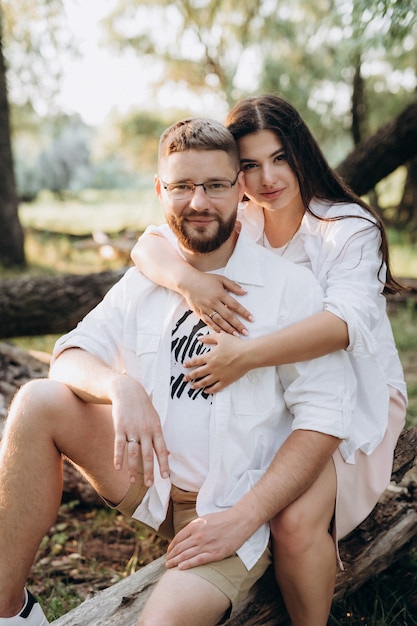 Young couple in love a guy with a beard and a girl with dark hair in light clothes in the green forest