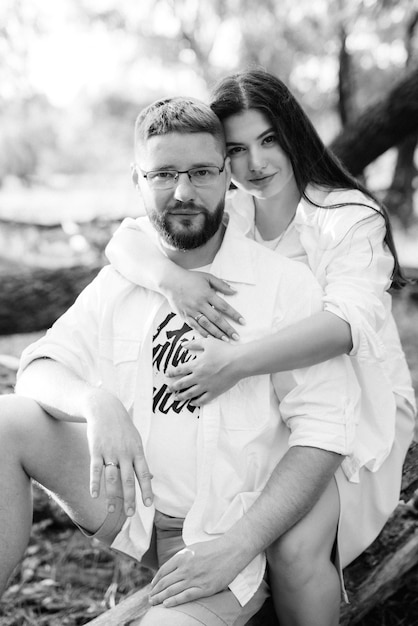 Young couple in love a guy with a beard and a girl with dark hair in light clothes in the green forest