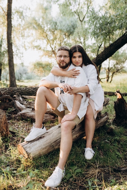 Young couple in love a guy with a beard and a girl with dark hair in light clothes in the green forest