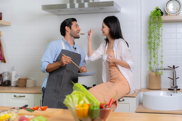 A young couple in love having fun while preparing a breakfast together on a beautiful morningThe woman feeding the man