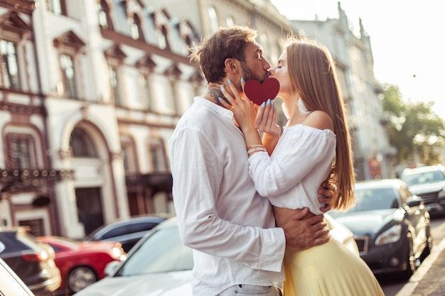 Young couple in love hold a red heart show their love and kiss in the city Romantic concept