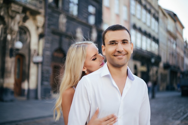 Young couple in love hug each other on city background