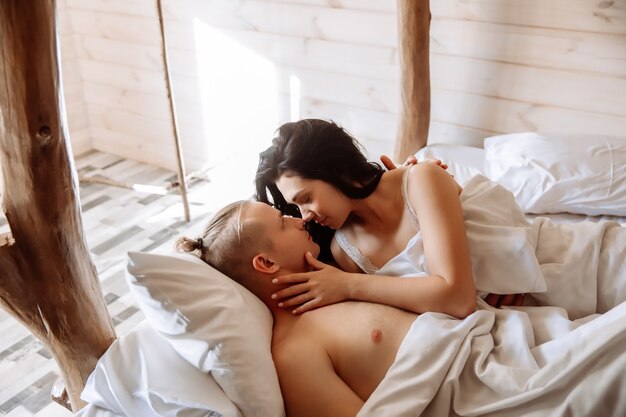 Young couple in love man and woman lie in bed under a white blanket they look at each other