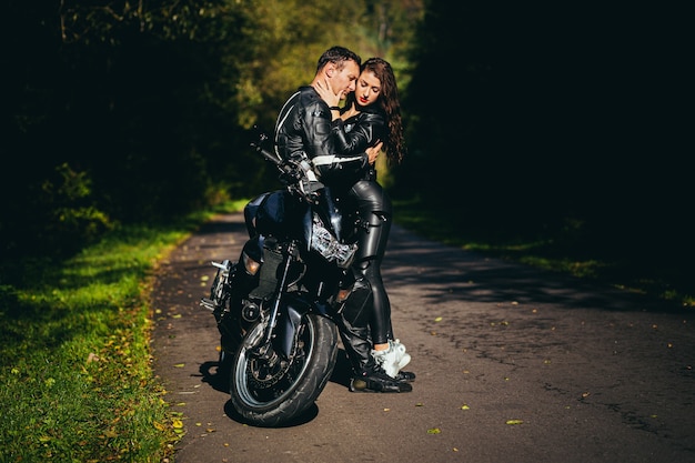 young couple in love on a motorcycle on the road in the woods