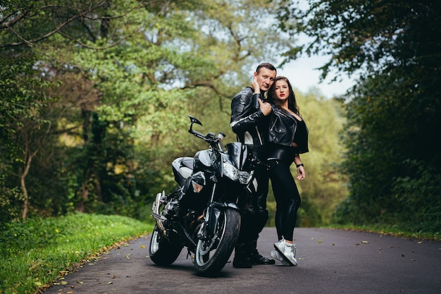 young couple in love on a motorcycle on the road in the woods