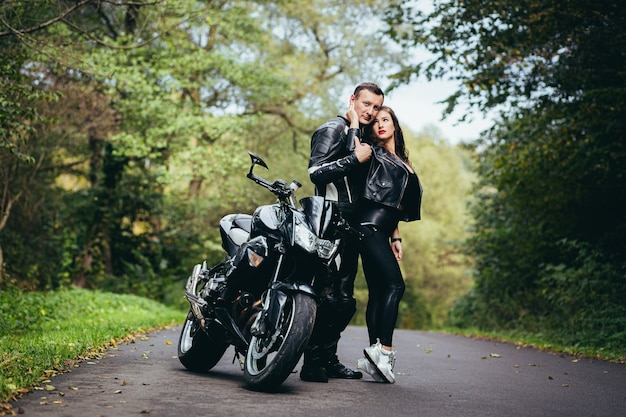 young couple in love on a motorcycle on the road in the woods