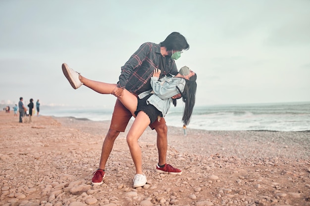 Young couple in love sitting on the beach during a beautiful sunset