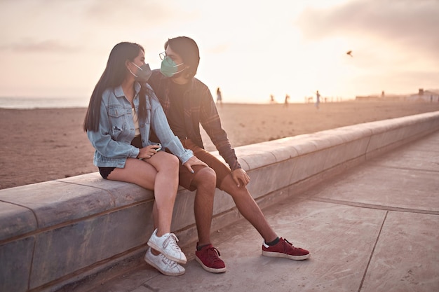 Young couple in love sitting on the beach during a beautiful sunset