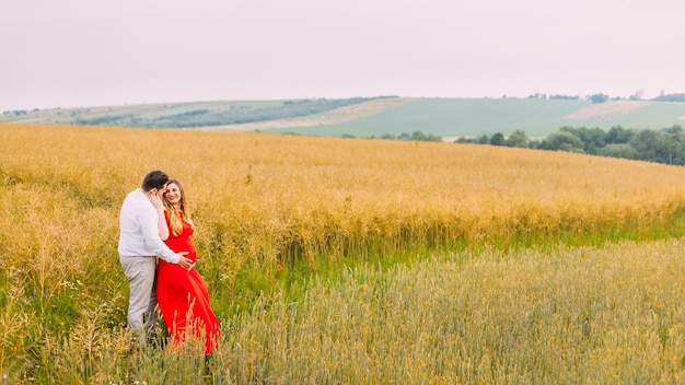 A young couple of lovers walking in a wheat golden field at sunset