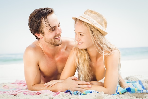 Young couple lying on the beach and talking to each other