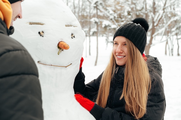 Young couple made a snowman in a snowy park