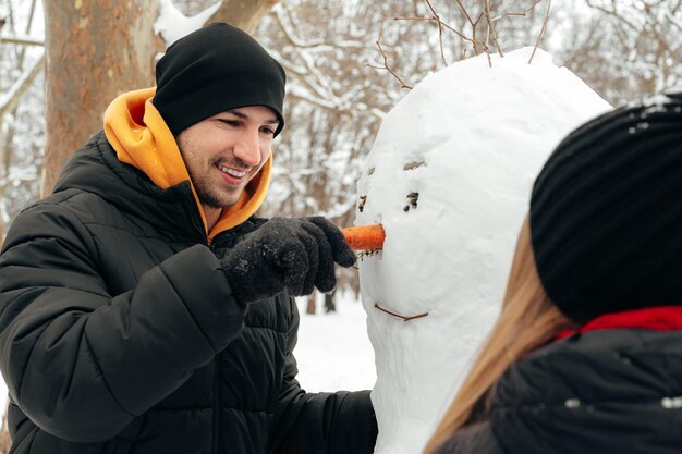 Photo young couple made a snowman in a snowy park