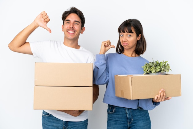 Young couple making a move while picking up a box full of things isolated on white background proud and selfsatisfied in love yourself concept