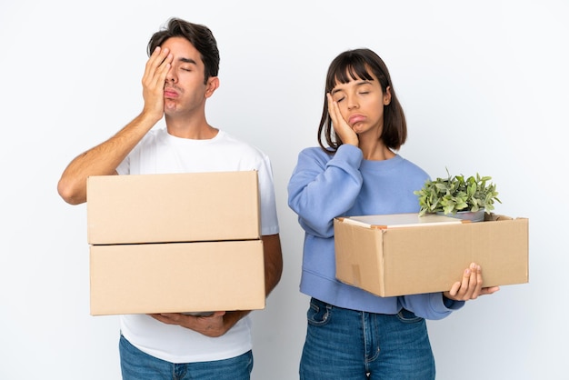 Young couple making a move while picking up a box full of things isolated on white background with surprise and shocked facial expression