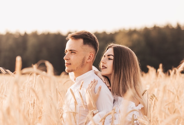 A young couple man and woman hug with tenderness in nature in the summer. Lovers