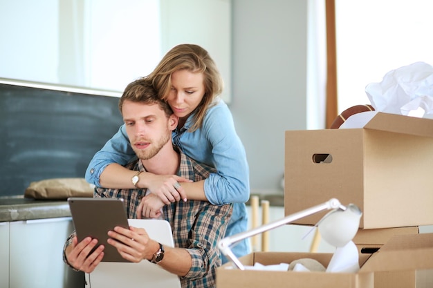 Young couple moving in new homeSitting and relaxing after unpackingLooking something on laptop Young couple