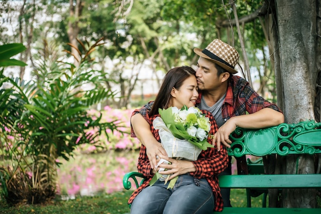 Young couple in nature sitting on bench, male and female together