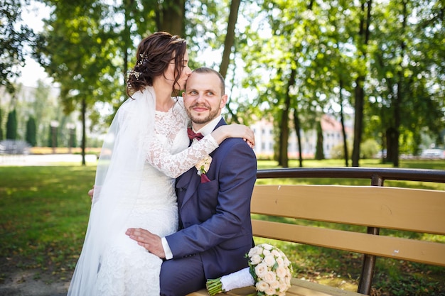 Young couple newlyweds kissing on a park bench