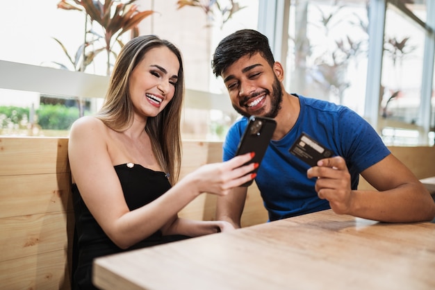 Young couple online banking using smartphone shopping online with credit card at balcony of your home lifestyle