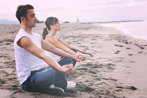 young couple people meditating yoga in lotus position at early morning on the beach