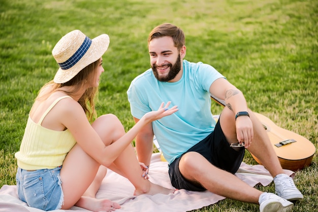 Young couple on the picnic in the park talking and relaxing