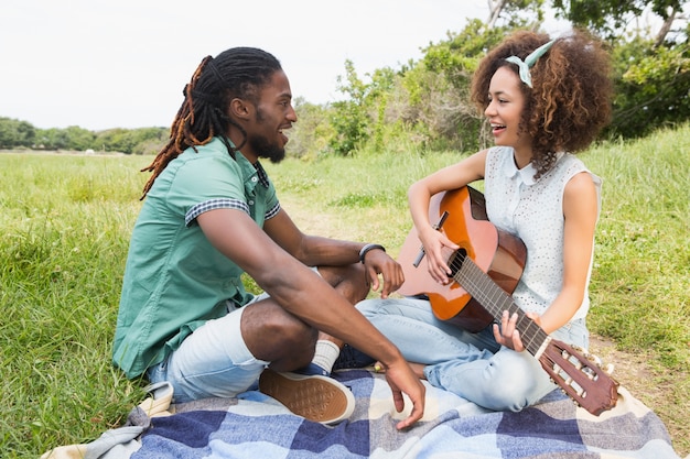 Young couple on a picnic playing guitar