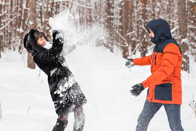 Young couple playing in snow, having snowball fight.