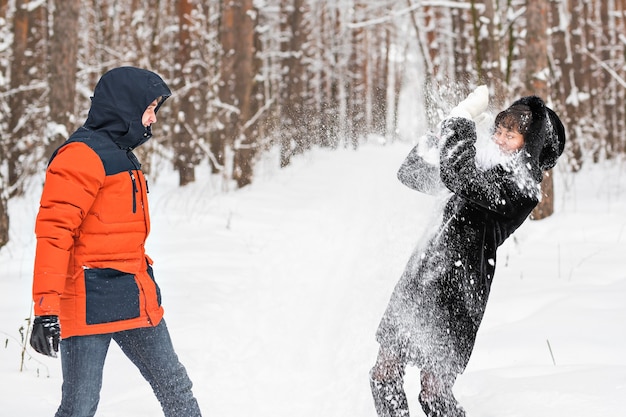 Young couple playing in snow, having snowball fight.