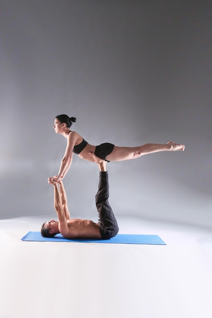 Young couple practicing acro yoga on mat in studio together Acroyoga Couple yoga Partner yoga