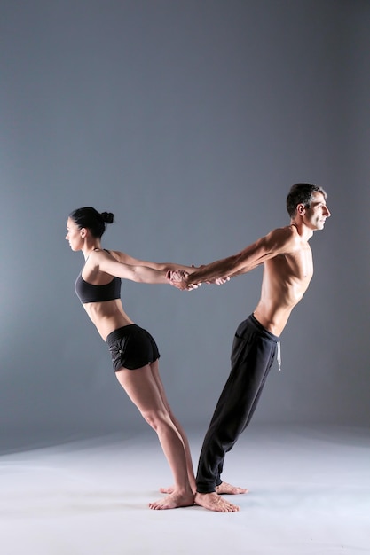 Young couple practicing acro yoga on mat in studio together Acroyoga Couple yoga Partner yoga