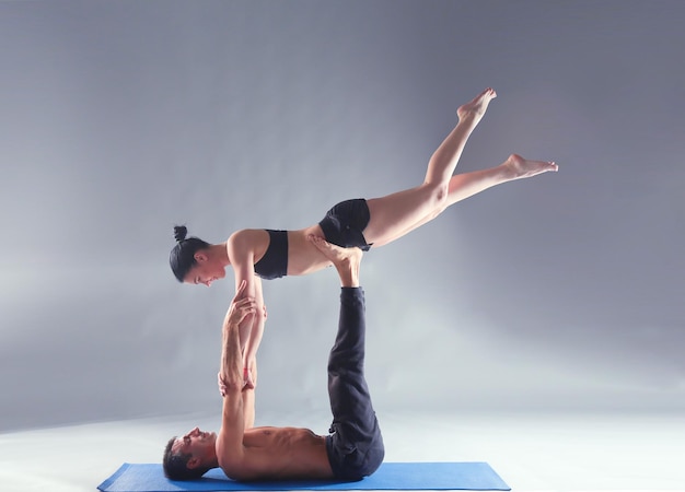 Young couple practicing acro yoga on mat in studio together Acroyoga Couple yoga Partner yoga