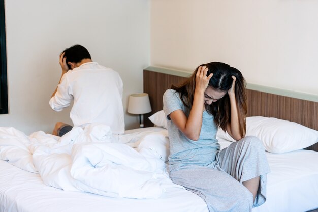 Young couple in quarrel sitting on bed at home