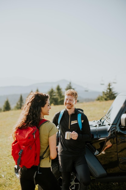 Young couple relaxing by a terrain vehicle hood at countryside