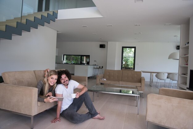 Young couple relaxing at luxurious home with tablet computers reading in the living room on the sofa couch.