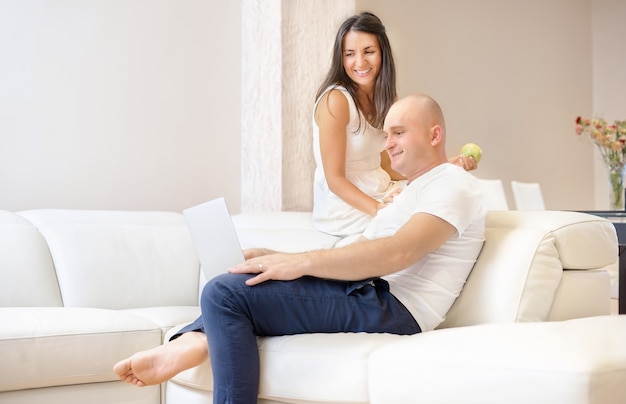 Young couple relaxing on sofa with laptop.Love,happiness,people and fun concept.