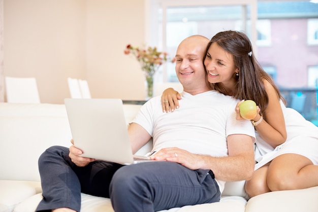 Young couple relaxing on sofa with laptop.Love,happiness,people and fun concept.