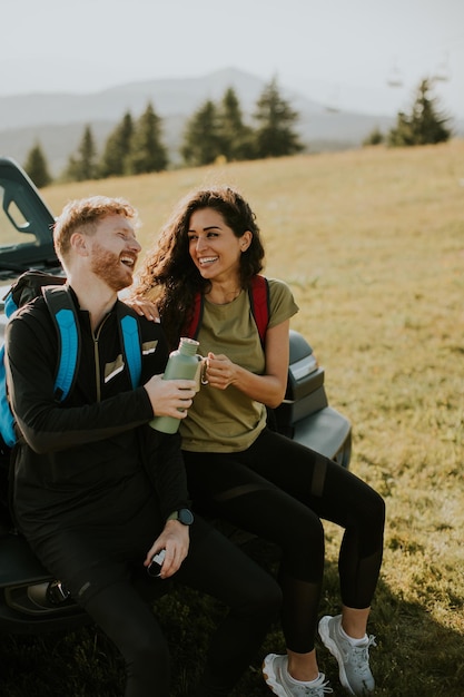 Young couple relaxing on a terrain vehicle hood at countryside