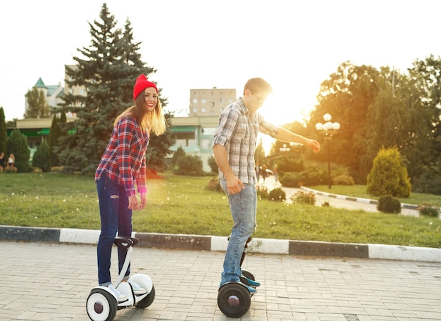 Photo young couple riding hoverboard