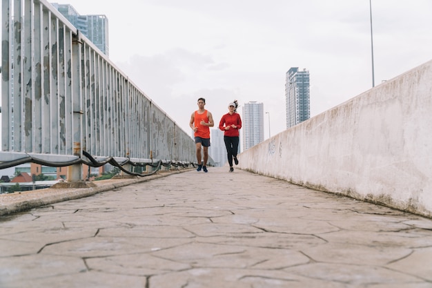 Young couple runner running on running road in city park;sport, people, exercising and lifestyle concept