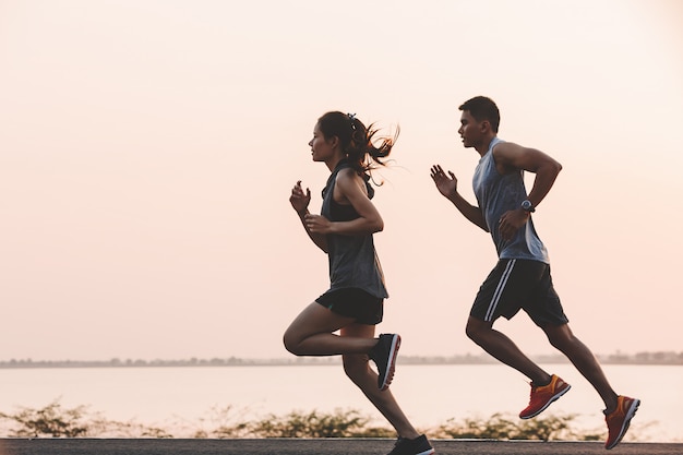 Young couple runner running on running road in city park