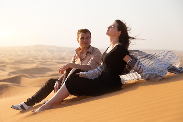 Photo young couple sitting on land against sky