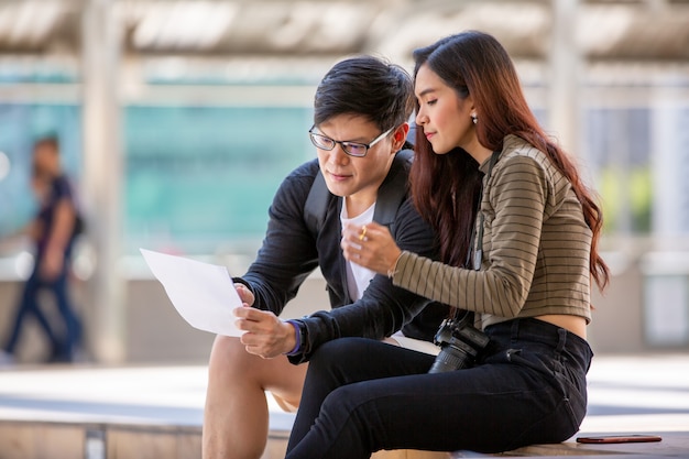 young couple sitting on staircase and looking on paper at outdoor