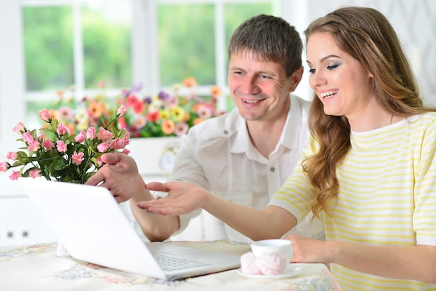 Young couple sitting at table and using laptop