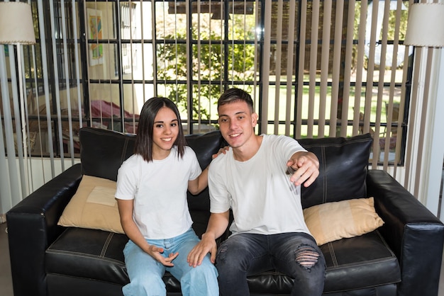 young couple sitting on their couch at home watching a football game