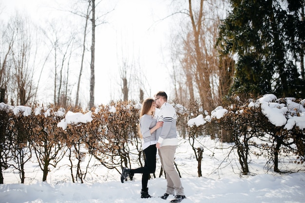 Young couple smile and kissing in the park in winter