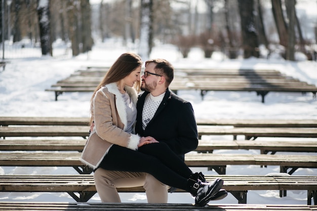 Young couple smile and kissing in the park in winter